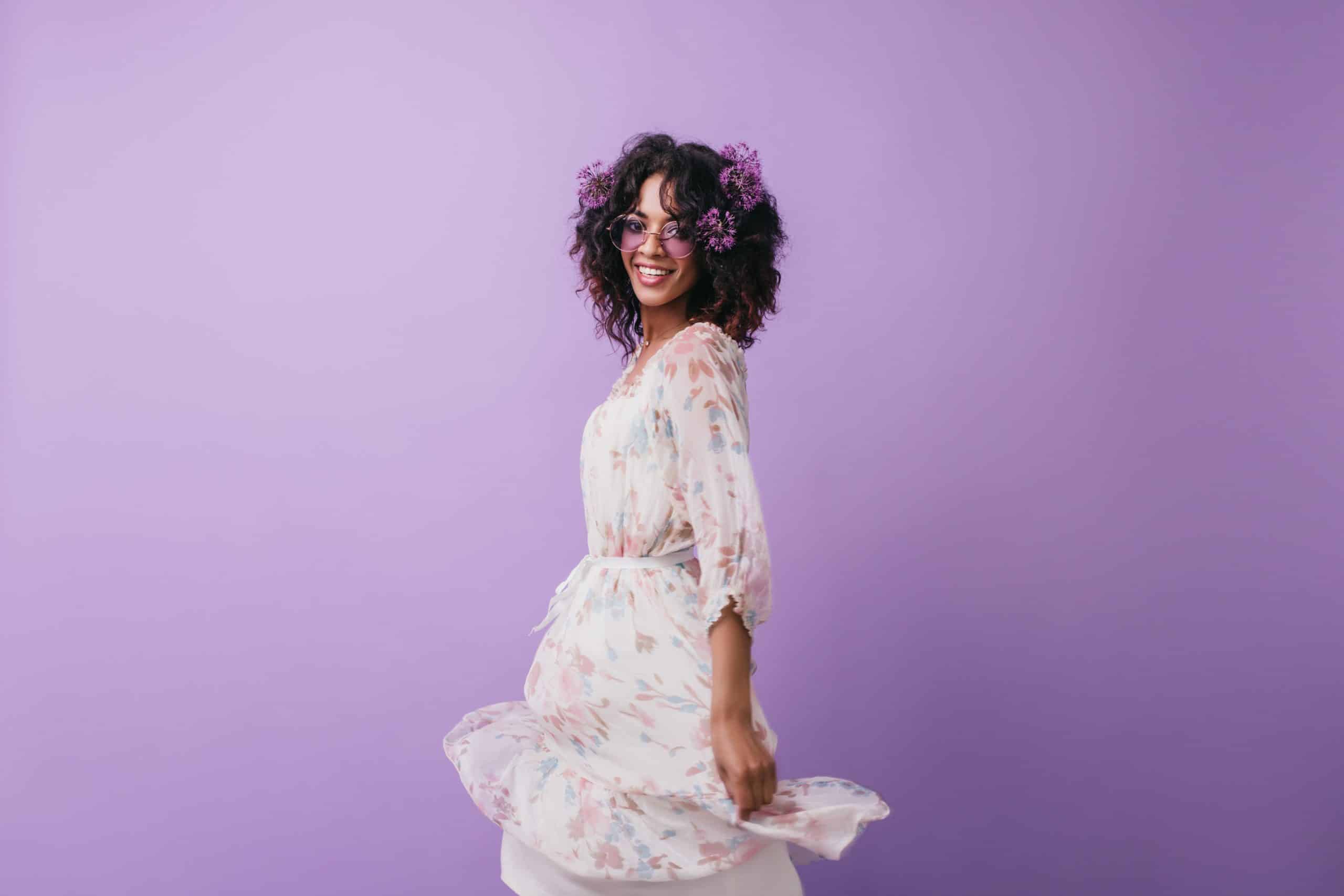 Fascinating african girl with flowers in hair posing in studio. Fashionable black female model in d